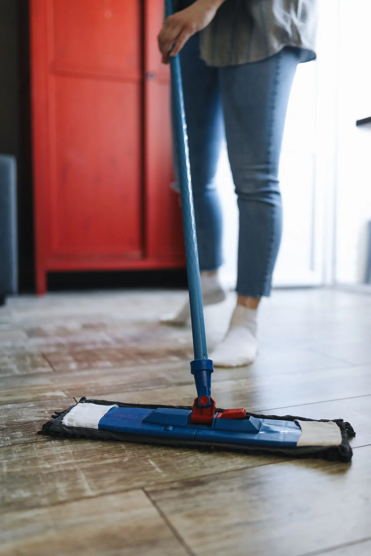 A person mopping a wooden floor at home