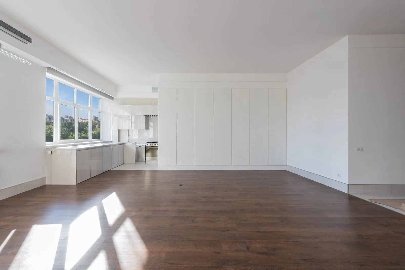 An empty, clean flat with a wooden floor and an open-plan kitchen