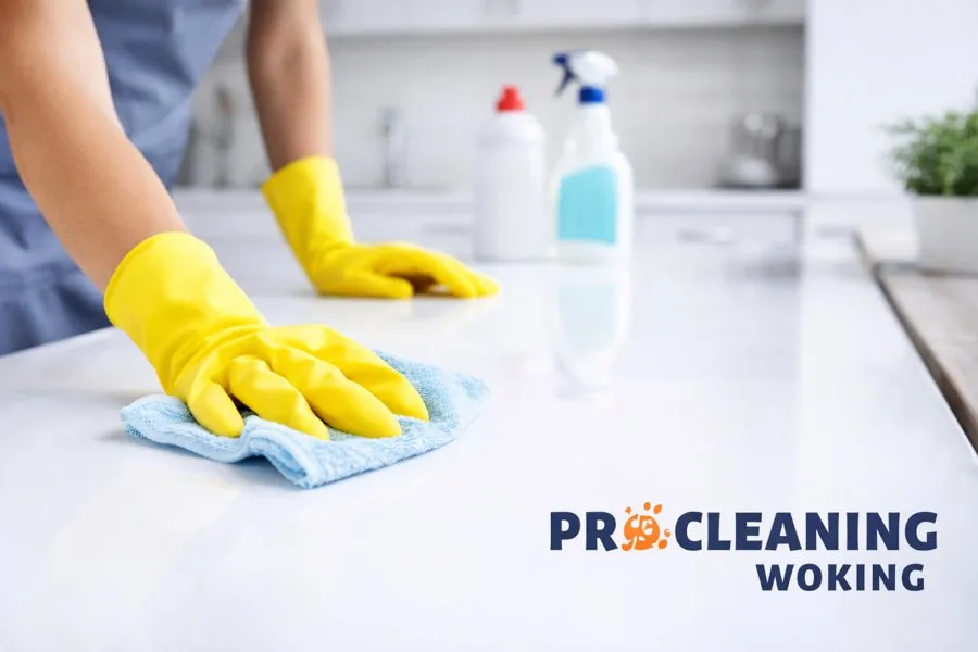Gloved hand wiping a white kitchen worktop with a blue cloth